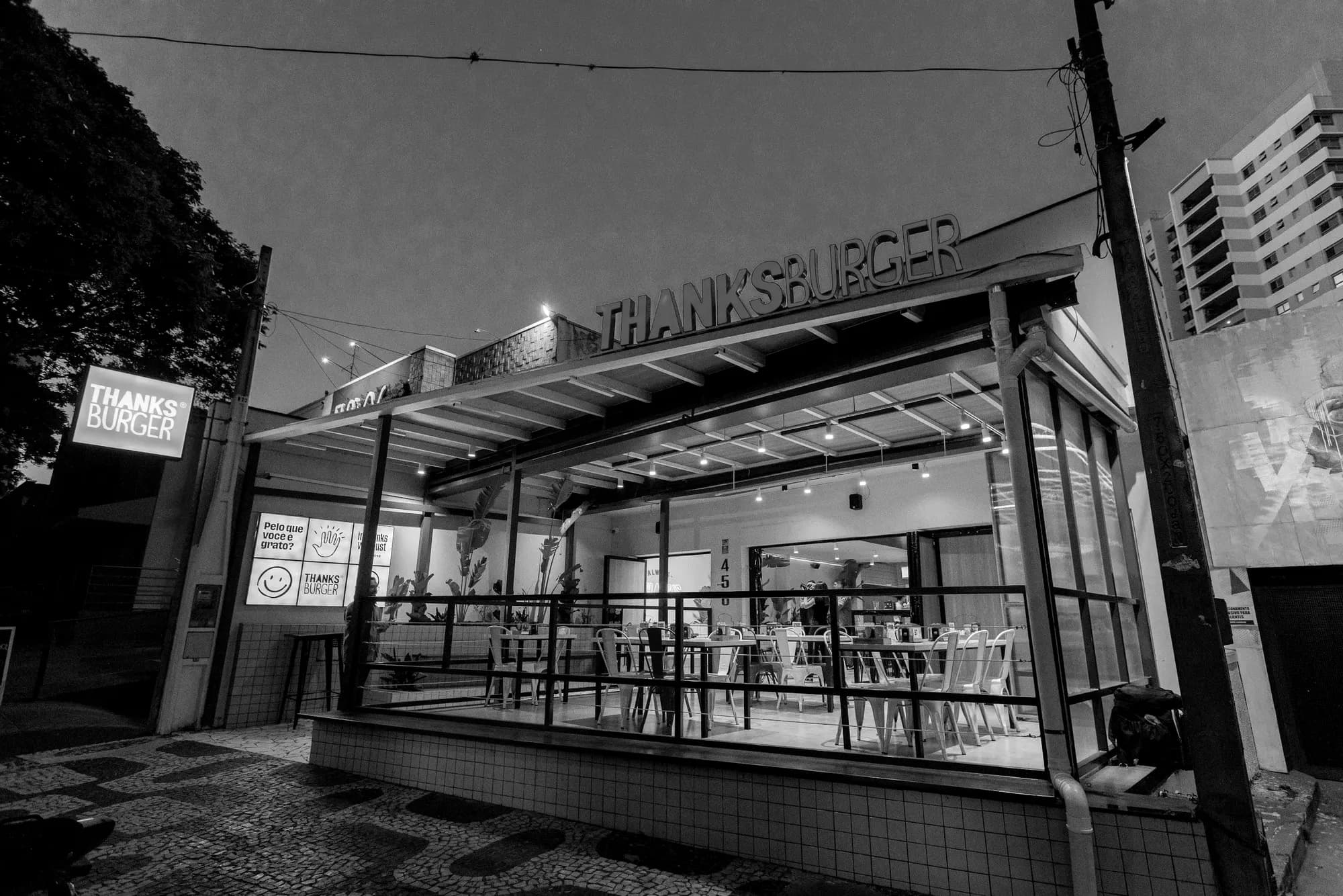Fachada do Thanks Burger à noite com o letreiro aceso