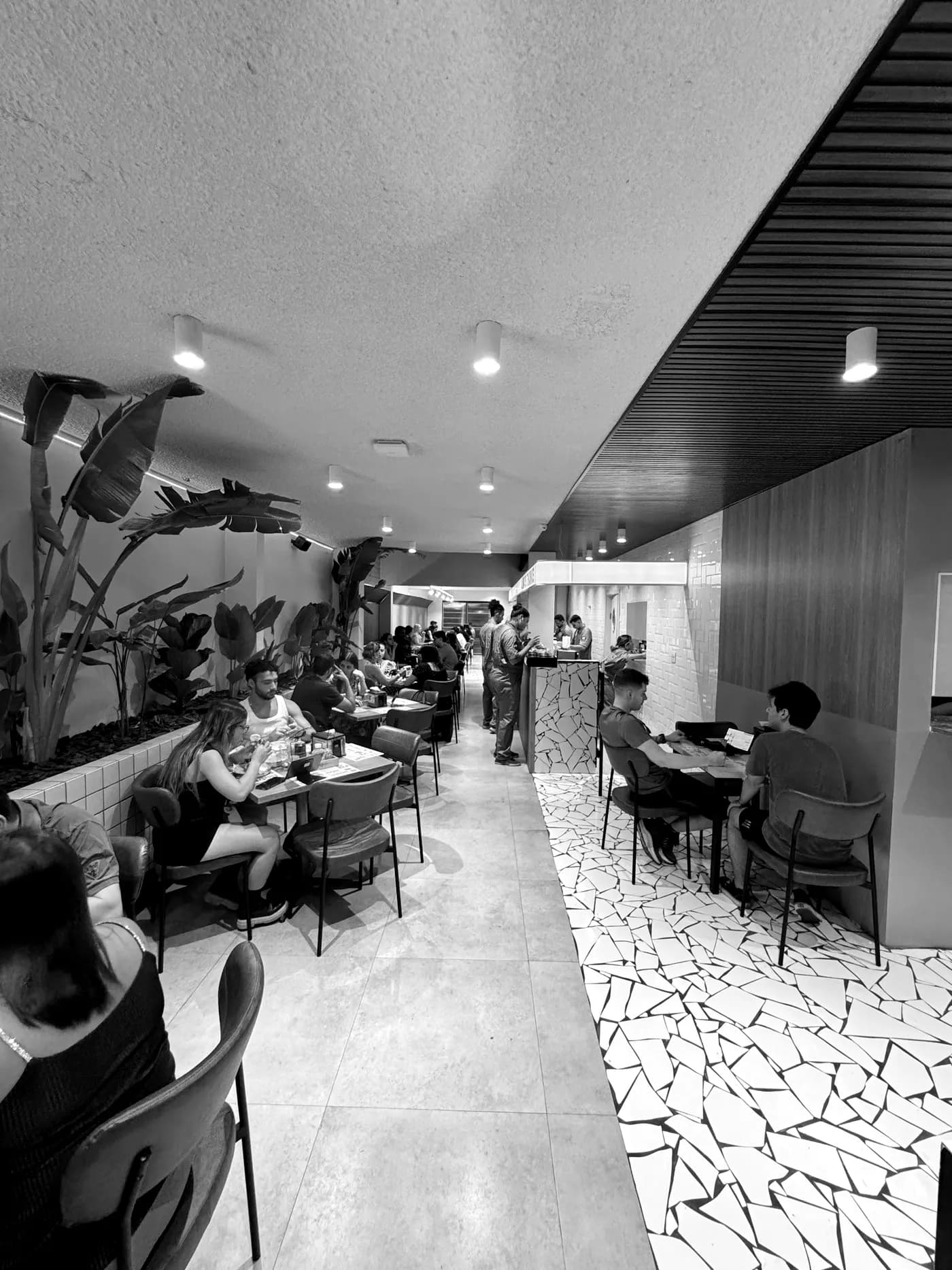 Salão do Thanks Burger cheio, com mesas ocupadas ao longo do corredor